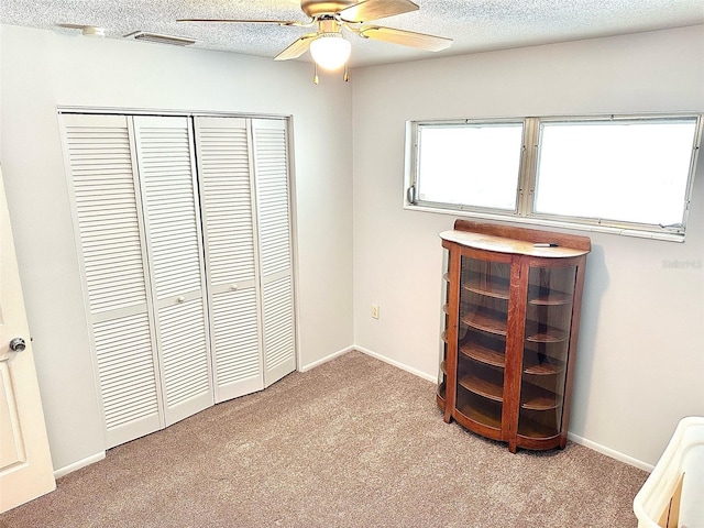 unfurnished bedroom with light colored carpet, a closet, ceiling fan, and a textured ceiling