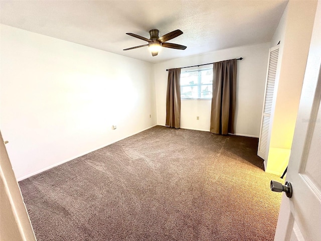 unfurnished room with dark carpet and ceiling fan