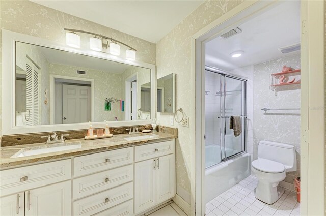 full bathroom featuring tile patterned floors, vanity, toilet, and bath / shower combo with glass door