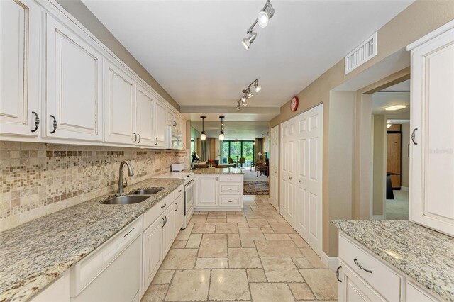 kitchen with dishwasher, sink, white cabinets, and hanging light fixtures