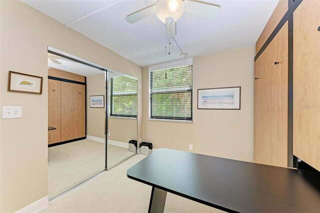 unfurnished office with ceiling fan and light colored carpet