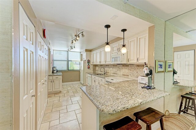 kitchen featuring kitchen peninsula, a breakfast bar, decorative light fixtures, and sink