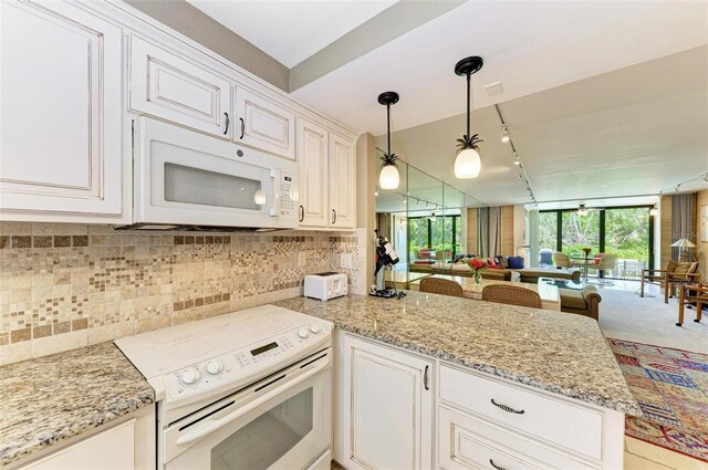 kitchen with kitchen peninsula, light stone countertops, rail lighting, and white appliances