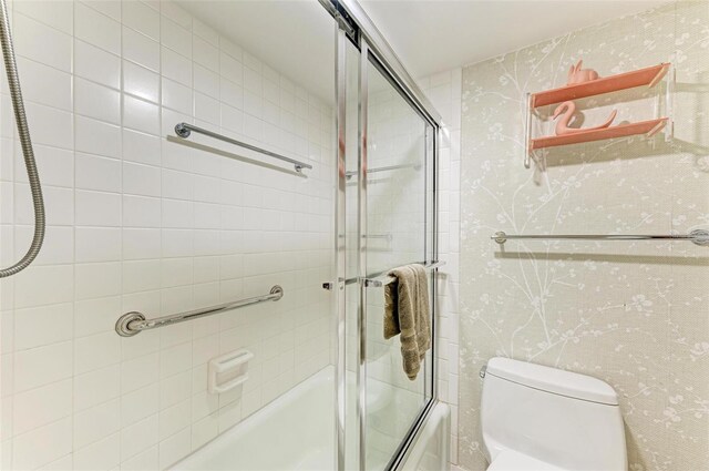 bathroom featuring enclosed tub / shower combo and toilet