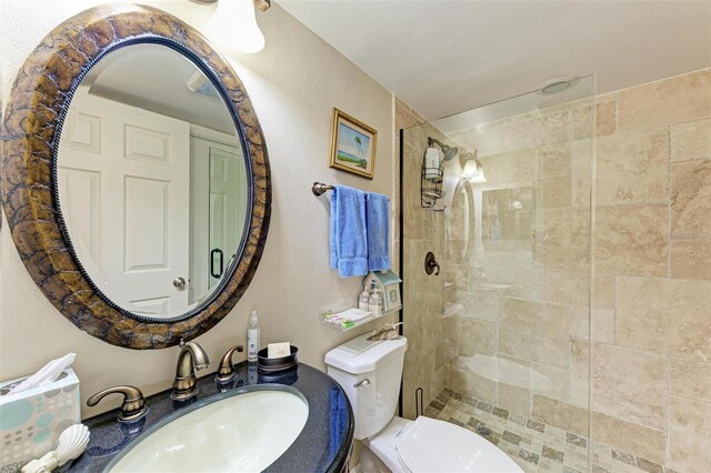 bathroom featuring a tile shower, toilet, and sink