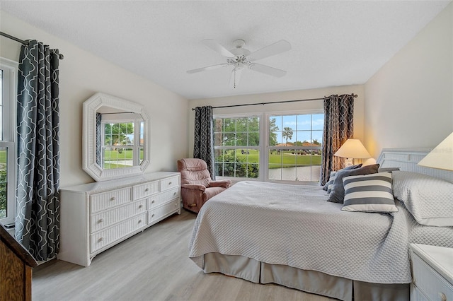 bedroom featuring ceiling fan, multiple windows, and light hardwood / wood-style flooring