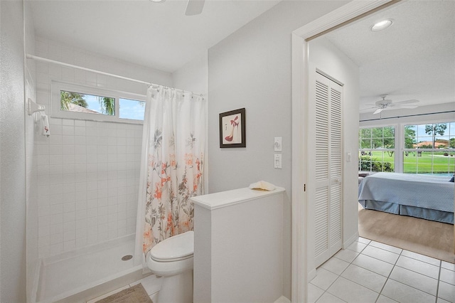 bathroom with tile floors, ceiling fan, toilet, and curtained shower