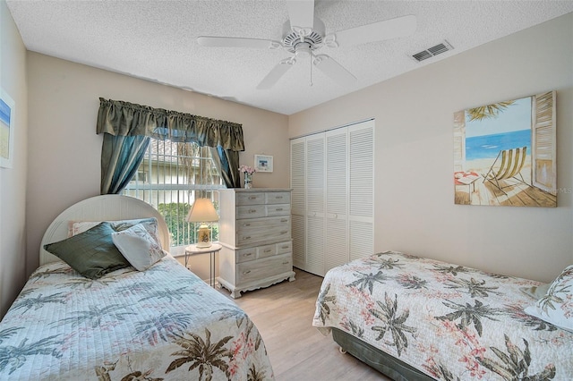 bedroom with a closet, ceiling fan, light hardwood / wood-style flooring, and a textured ceiling