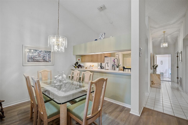 dining area with high vaulted ceiling, a notable chandelier, and tile floors