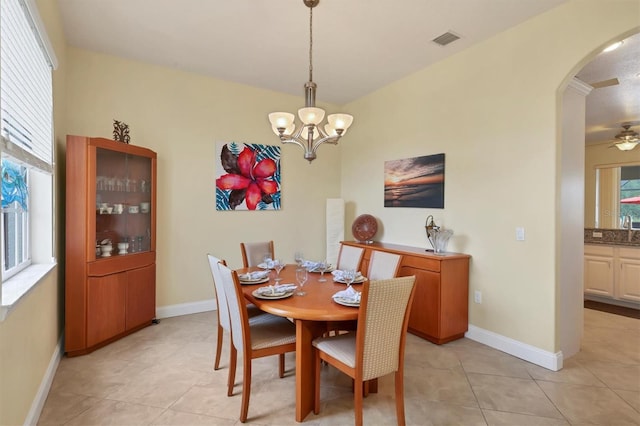 tiled dining area featuring ceiling fan with notable chandelier and a wealth of natural light