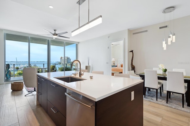 kitchen with pendant lighting, a center island with sink, sink, light hardwood / wood-style flooring, and ceiling fan