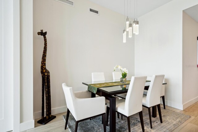 dining space with light wood-type flooring and an inviting chandelier