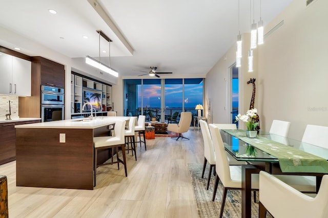 kitchen with white cabinets, ceiling fan, hanging light fixtures, and light hardwood / wood-style flooring