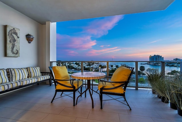 balcony at dusk with an outdoor hangout area and a water view