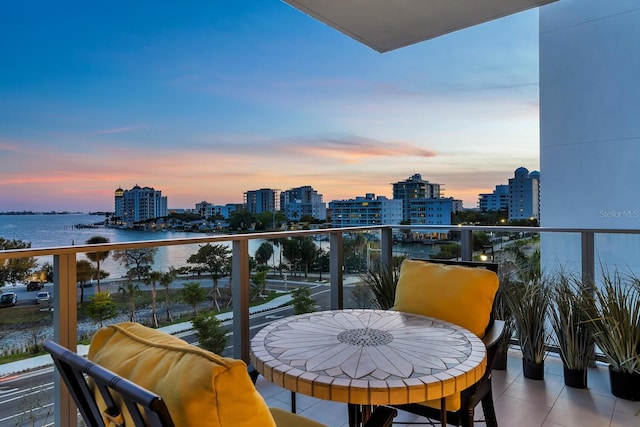 balcony at dusk featuring a water view