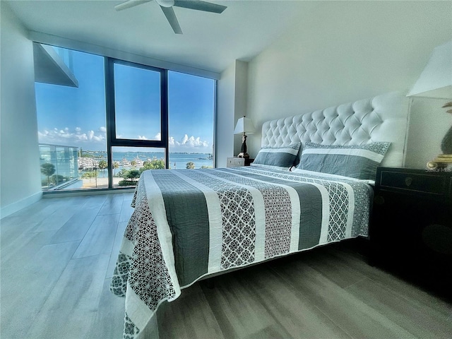 bedroom with ceiling fan, expansive windows, and hardwood / wood-style flooring