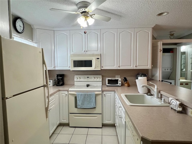 kitchen featuring light tile floors, sink, ceiling fan, stacked washing maching and dryer, and white appliances