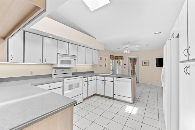 kitchen with a skylight, ceiling fan, white appliances, light tile floors, and white cabinets