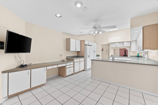 kitchen featuring white fridge with ice dispenser, white cabinets, kitchen peninsula, ceiling fan, and light tile flooring