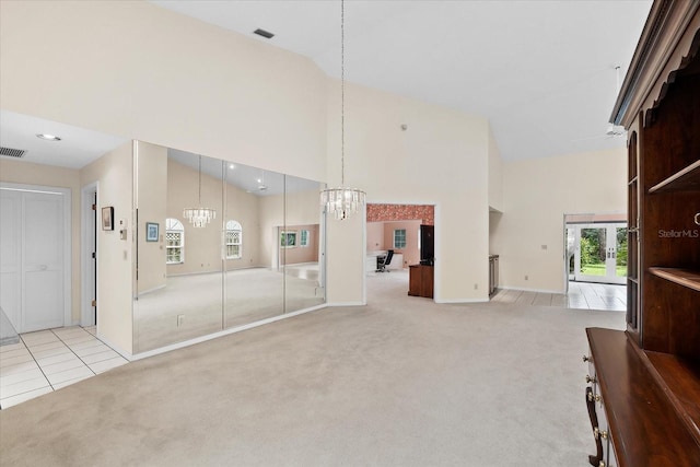 unfurnished living room featuring high vaulted ceiling, light colored carpet, and a notable chandelier