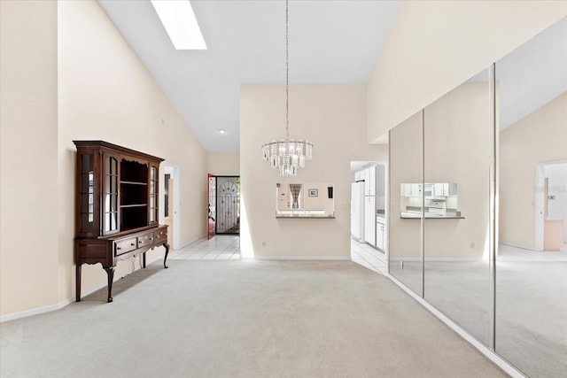 unfurnished dining area with a chandelier, high vaulted ceiling, light colored carpet, and a skylight