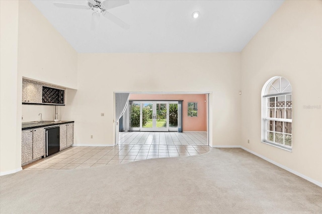 unfurnished living room with ceiling fan, light carpet, and high vaulted ceiling