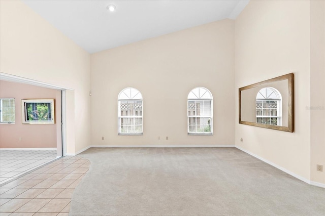 carpeted empty room with high vaulted ceiling and a wealth of natural light