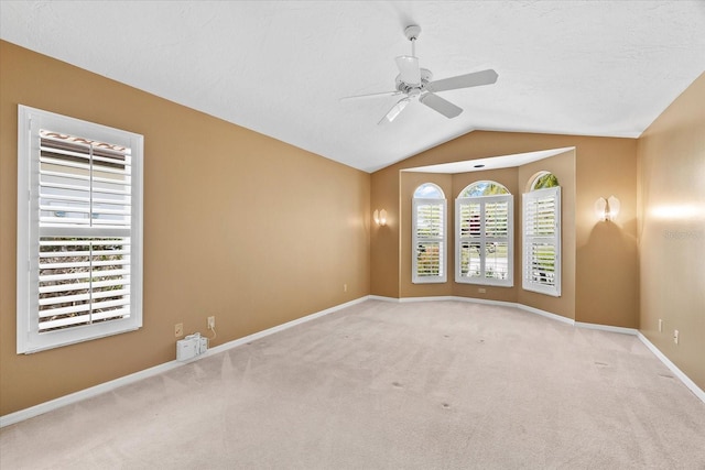 carpeted spare room featuring ceiling fan and vaulted ceiling