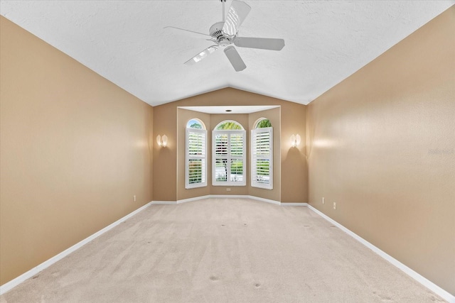 carpeted empty room with vaulted ceiling, a textured ceiling, and ceiling fan