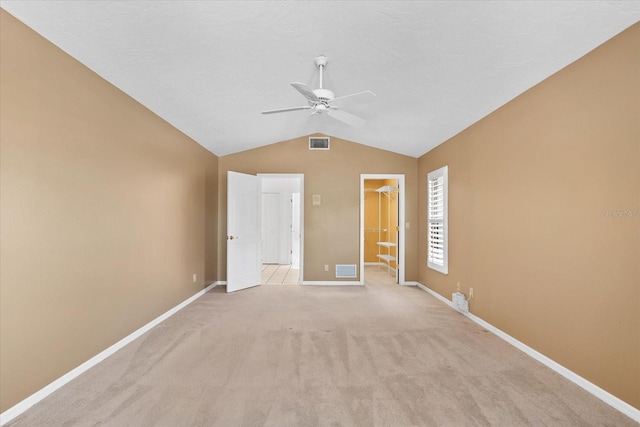 spare room featuring light carpet, vaulted ceiling, and ceiling fan