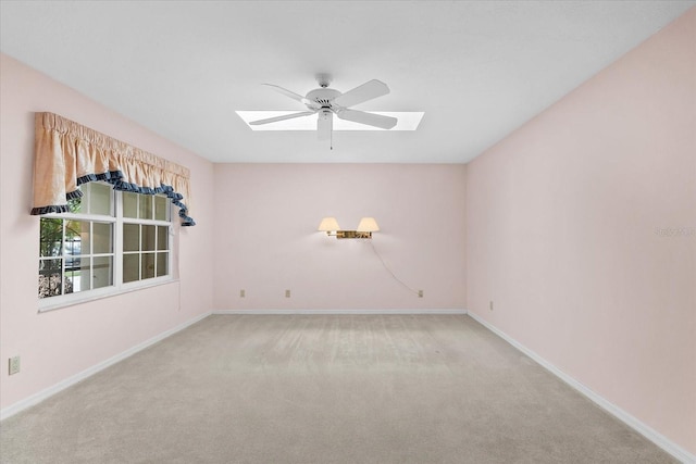 carpeted spare room featuring ceiling fan and a skylight