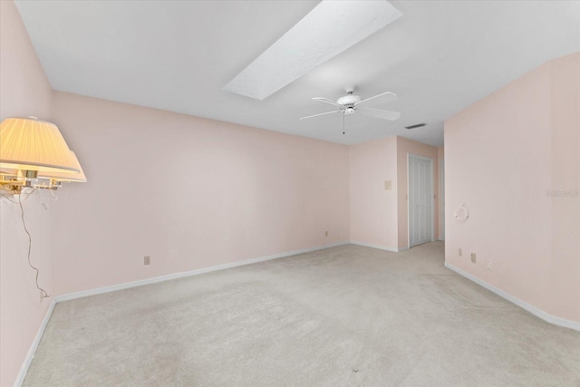 carpeted empty room featuring ceiling fan and a skylight