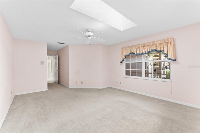 unfurnished room with light carpet, ceiling fan, and a skylight