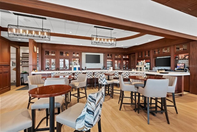 dining area with light wood-type flooring and a raised ceiling