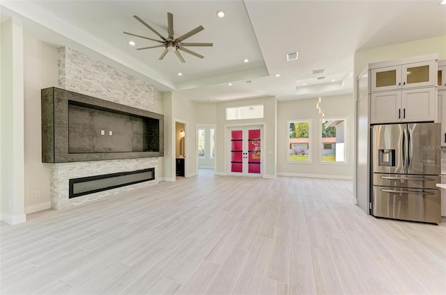 living room featuring light wood-type flooring, a tray ceiling, ceiling fan, and a fireplace