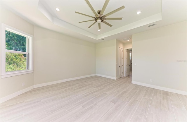 unfurnished room with ceiling fan and a tray ceiling