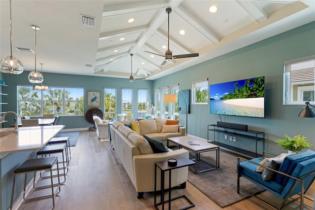 living room featuring ceiling fan, beamed ceiling, light hardwood / wood-style floors, and high vaulted ceiling