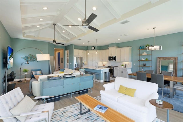 living room with hardwood / wood-style floors, lofted ceiling with beams, ceiling fan, and sink