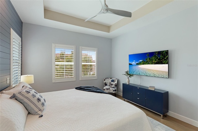 bedroom with hardwood / wood-style floors, a tray ceiling, and ceiling fan