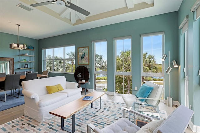 sunroom with ceiling fan and a tray ceiling