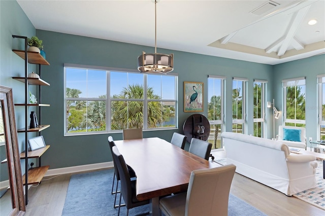 dining space featuring beamed ceiling, a notable chandelier, and wood-type flooring