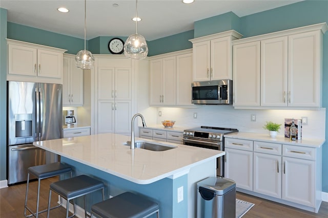 kitchen featuring an island with sink, stainless steel appliances, white cabinetry, and sink