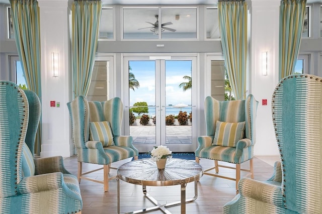 living area featuring ceiling fan, a high ceiling, and light hardwood / wood-style flooring