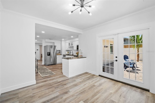 kitchen with light wood-type flooring, french doors, white cabinetry, kitchen peninsula, and stainless steel fridge