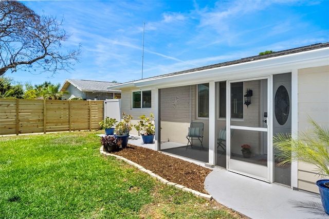 back of property with a sunroom and a lawn