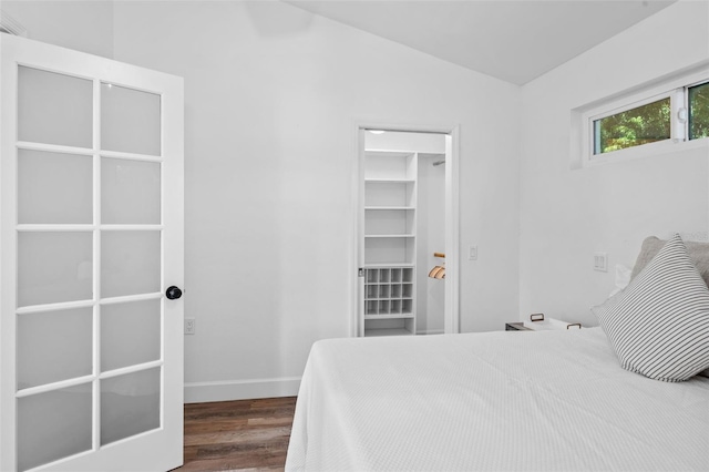 bedroom with lofted ceiling, a spacious closet, and wood-type flooring