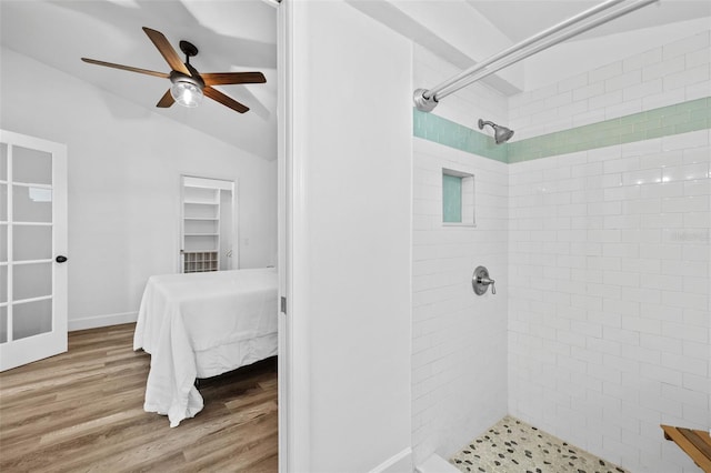 bathroom featuring ceiling fan, tiled shower, vaulted ceiling, and wood-type flooring