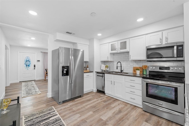 kitchen featuring tasteful backsplash, light wood-type flooring, stainless steel appliances, and sink