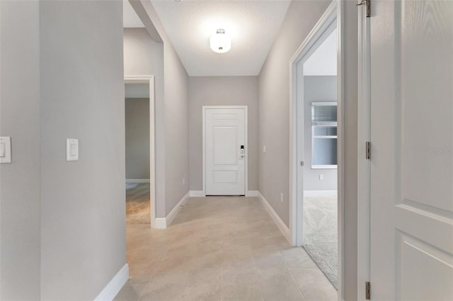 hall featuring light carpet and a textured ceiling