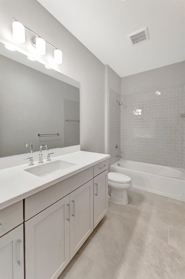 full bathroom with tiled shower / bath, tile patterned flooring, vanity, and toilet